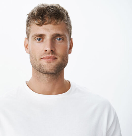 waist-up-shot-handsome-calm-blond-blue-eyed-guy-with-bristle-white-t-shirt-looking-front-with-relaxed-carefree-facial-expression-posing-gray-wall-looking-sincere-chill 1-1